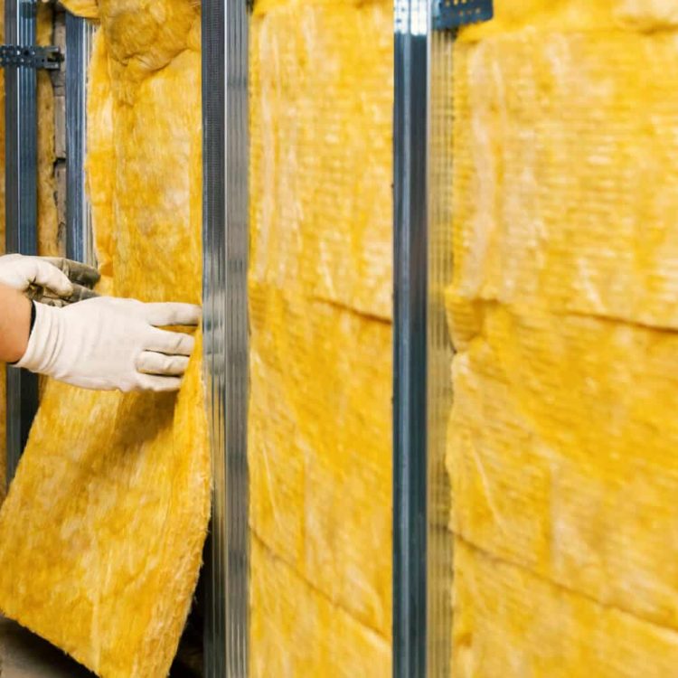 house wall insulation. construction worker installing glass wool into the metal profile frame indoors. banner with copy space